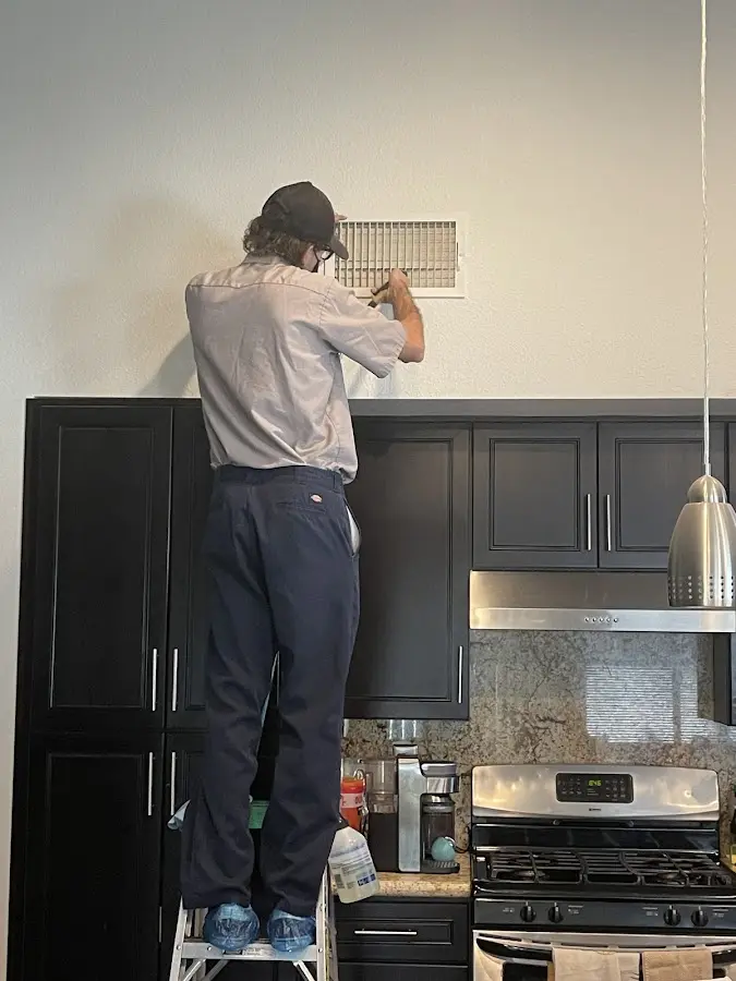 Technician inspecting an air vent during HVAC service in Orchard Park